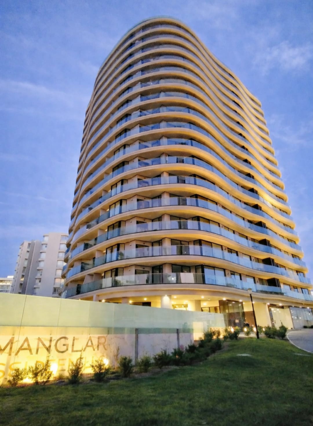 Fachada del edificio de Manglar Brava iluminada al atardecer, con su arquitectura orgánica de balcones curvos.